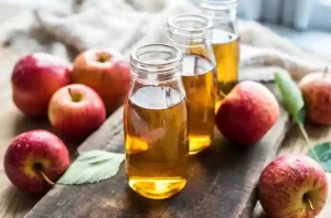 Apple cider vinegar in a glass jar with cotton pads and a spray bottle