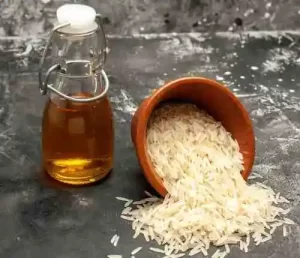 Bowl of rice beside a clear toner bottle on a bamboo mat