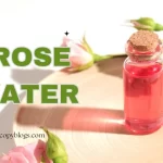 Homemade rose water toner in glass bottle with fresh rose petals on wooden table – natural skincare remedy.