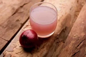 Fresh onion juice in a glass bowl with sliced onions.