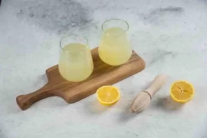 Fresh lemon juice in a bowl with sliced lemons.